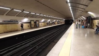 Lizbon, Portekiz - 10 Ekim 2019: Kırmızı metro treni Lizbon 'daki yeraltı istasyonuna kemerli tavan ve parlak ışıklandırmayla geliyor, yolcular sarı güvenlik hattının arkasında yolcu bekliyor.
