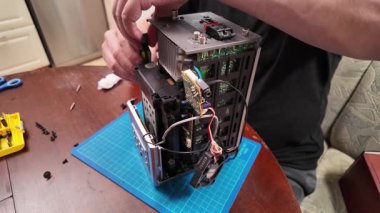 Bir kişi, bir atölye ayarı araçları kullanarak görünür devre kartları, kablolar ve bileşenleri olan parçalanmış bir elektronik cihazı onarmaya çalışır