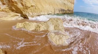 Güçlü okyanus dalgasının sahil kaya oluşumuyla çarpıştığı dramatik, yavaş çekim görüntüleri kristal berrak turkuaz sularda beyaz sprey ve köpükle altın kayalıklara çarpan muhteşem bir patlama yaratıyor.
