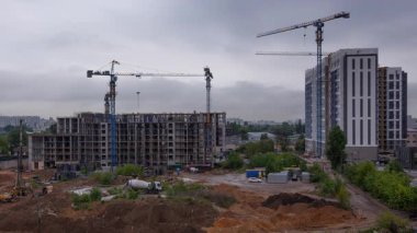 Büyük ölçekli kentsel gelişimin panoramik zaman çizelgesi farklı aşamalarda konut kompleksi inşa eden, modern mülk geliştirme ve inşaat endüstrisinin gelişmekte olduğunu gösteren çoklu kule vincini gösteriyor.