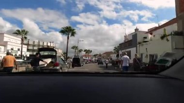 Ferragudo, Portekiz - 13 Ekim 2019: Ferragudo Algarve Portekiz 'in güneşli sokak manzarası palmiye ağaçları, insanlar ve mavi gökyüzü ile hareket eden bir arabadan, seyahat ve turizm içeriği için mükemmel