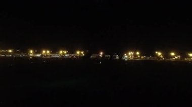 Gece aydınlanan havaalanı penceresinden, havalanının kalkış pistine giden uçak taksilerinin karanlık arka planda parlayan havalimanı altyapısını gösteren zaman aralığı.