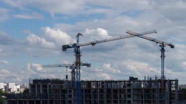 Kule vinçleri mavi gökyüzünün altında konut kompleksi inşa eder. Mülk mülkiyeti ve konut yatırımı isteyen müstakbel ipotek alıcıları için rüya ev geliştirme projelerini gösterirler.