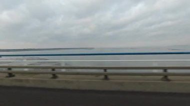 Portekiz, Lizbon 'daki Vasco da Gama Köprüsü' ndeki hareket halindeki bir araçtan çekilen Tagus Nehri 'nin bulanık hareket görüntüsü bulutlu bir gökyüzünün altındaki geniş su yolunu gösteriyor.