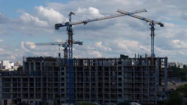 Kule turnaları, müstakbel ev sahipleri ve gayrimenkul yatırım hayalleri için emlak geliştirme sürecini gösteren açık yaz gökyüzü altında konut kompleksi inşa ederler.