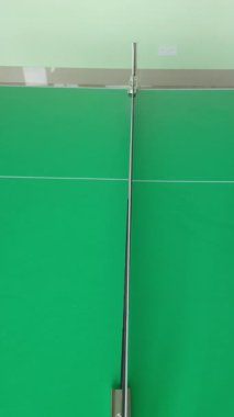 Profesyonel yeşil masa tenisi kortunun kapalı kapılar ardında rekabetçi spor oyunları ve eğlence amaçlı antrenman aktiviteleri için net olarak hazır görünümü