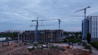 Yatay zaman dilimi videosu, gündüz gece geçiş olarak kule vinçleri olan bir inşaat alanı gösteriyor. Şehir ışıkları ufuk çizgisini yavaş yavaş aydınlatırken inşaat malzemeleri inşaat alanında hareket ediyor.