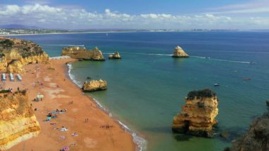 Portekiz 'in Algarve kentindeki Praia da Marinha, eşsiz kaya oluşumlarıyla çevrili altın uçurumları ve turkuaz suları olan ikonik bir plajdır. Sonbahar rahatlama ve nefes kesici fotoğrafçılık için mükemmel..
