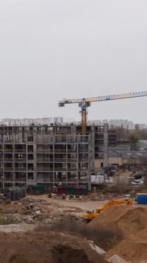 Yapı vinçlerinin dikey formatı çok katlı kompleks bir gelişimin üzerinde faaliyet göstererek, kentsel bir ortamda modern mülk inşaatının dinamik sürecini gözler önüne seriyor.