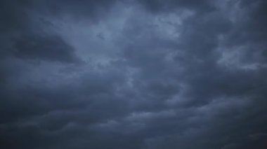 Gökyüzünde hareket eden kara fırtınalı bulutların dramatik zamanlaması. Bu sinematik ve karamsar arka plan doğanın uğursuz gücünü ve değişen havayı yakalar.