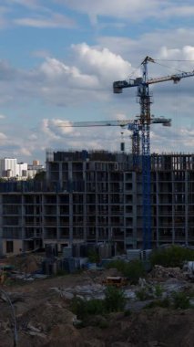 Kule vinçleri bulutlu gökyüzünün altında konut binaları inşa ediyor. Müstakbel ev sahipleri için emlak yatırım fırsatları arayan gayrimenkul geliştirme çalışmalarını gösteriyor.