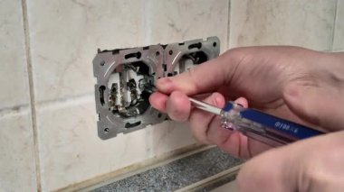 Yeni bir elektrik prizi takan bir adamın yakın çekim videosu. Bir elektrikçi, elektrik güvenliği ve bakımı için ev geliştirme ve DIY onarımı yapar