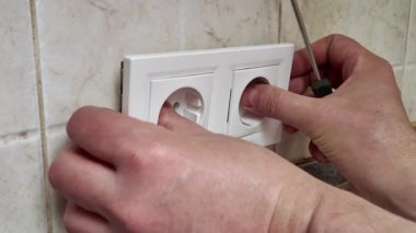 Mutfağa yeni bir duvar soketi takan bir elektrikçinin yakın çekimi. Güvenlik ve bakım için ev geliştirme ve DIY elektrik onarımı