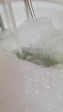 Küvete akan suyun dikey görüntüsü, yüzeyde köpük formları, modern banyo, hijyen, rahatlama, ev konforu, beyaz, dikey format