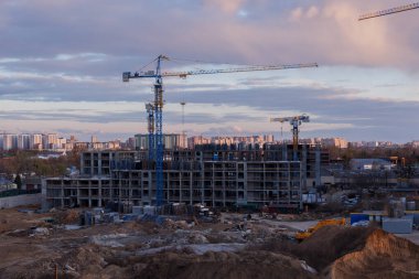 Gün batımında vinç ve makineli kentsel inşaat alanı, şehir gelişimi, takım çalışması ve mimari ilerlemesi dramatik bulutlu gökyüzü altında