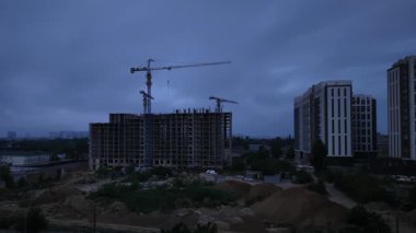 Şafak sökmeden önce vinçler ve tamamlanmamış binalarla inşaat alanı silueti zaman aşımının ilk aşamasını işaret ediyor.