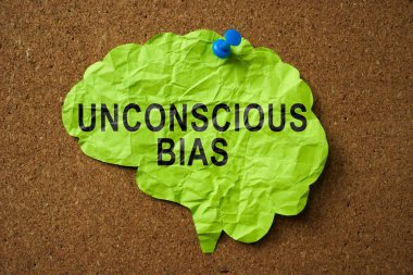 A Brain made of paper with the inscription Unconscious Bias pinned to the board. clipart