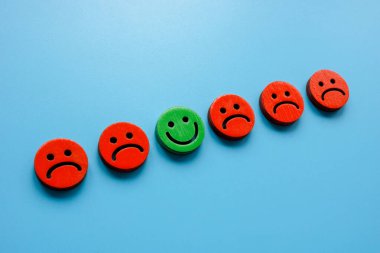 Line of sad emoticons and one happy as a symbol of positivity.