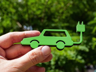 Closeup of hand holding model of electric car. clipart