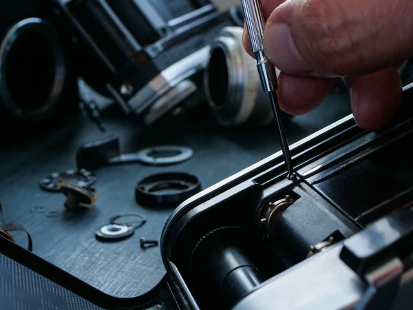 用螺丝起子密切合作 修理一台旧的电影摄影机 — 图库照片