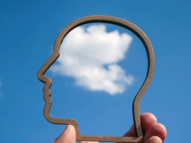 Farkındalık ve refah kavramı. El, başının dış hatlarını gökyüzüne karşı tutar..