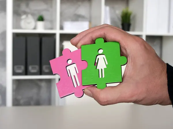 Hand holds puzzles with a man and a woman. Equal rights at work.