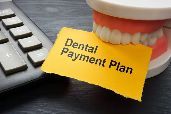 Dental payment plan concept. Calculator and jaws holding a sheet.
