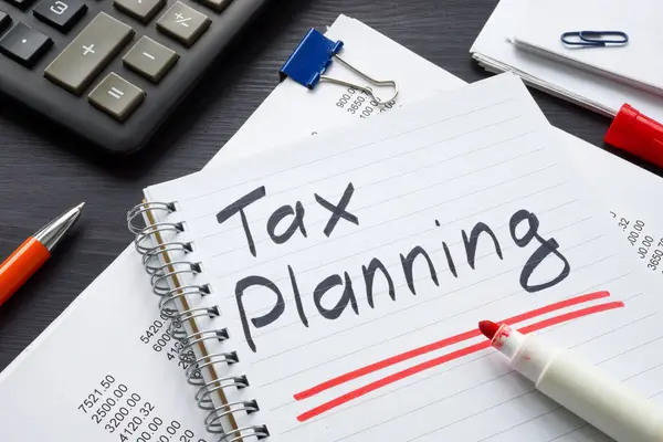 Financial documents and notepad with writing tax planning.
