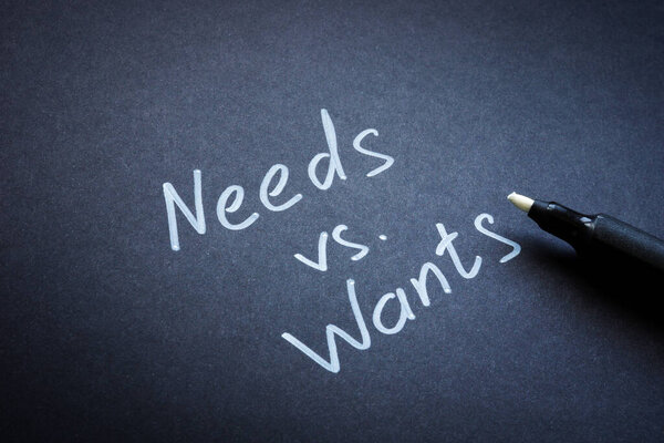 Нуждается против хочет концепцию. Слова на черной бумаге.