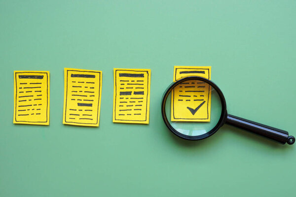 Документы и увеличительное стекло, представляющие сертификацию контроля качества.