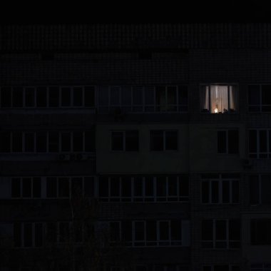 Rus bombardımanından sonra Kyiv 'in yerleşim alanındaki elektrik kesintisi sırasında çok katlı apartmanın pencerelerinden birinde ışık yandı.