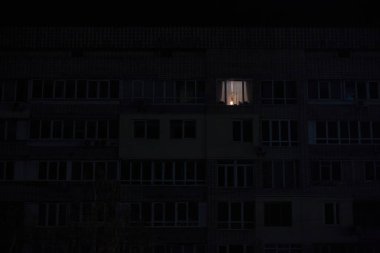 Rus bombardımanından sonra Kyiv 'in yerleşim alanındaki elektrik kesintisi sırasında çok katlı apartmanın pencerelerinden birinde ışık yandı.