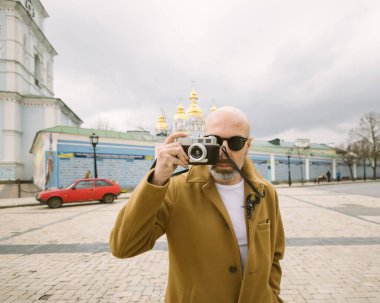 Yakışıklı sakallı fotoğrafçı Ukrayna 'nın Kyiv şehrindeki film retro kamerasında resim çekiyor.