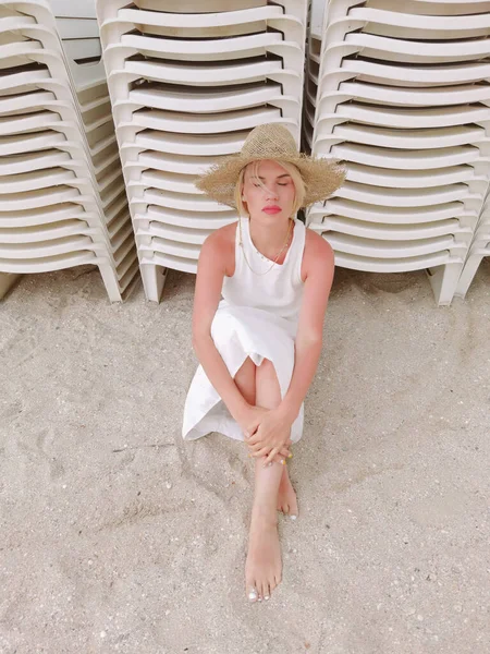 藁帽子をかぶった若い女性のファッションの肖像 コピースペースとビーチに座って官能的な女の子 魅力的な女の子見ますカメラ — ストック写真