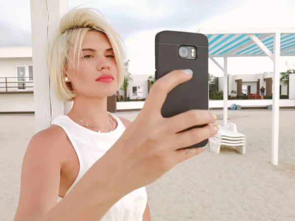 Genç Sarışın Kız Sahildeki Akıllı Telefonun Yanında Selfie Çekiyor — Stok fotoğraf