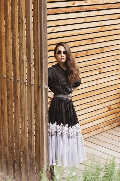穿着时髦服装 黑色连衣裙 站在街上的年轻时髦女人的生活方式肖像 木材背景 — 图库照片