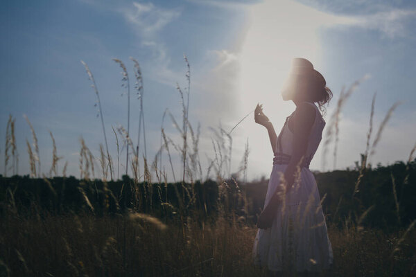 Silhouette of a beautiful woman on field at sunny day