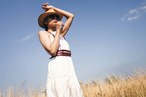 自由の精神 青い空を背景に畑に立っているブラウス サングラスの魅力的なBohoの女の子 夏休み旅行 ボヘミアンモダンなヒッピースタイル — ストック写真