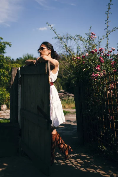 若いファッショナブルな女性は田舎の家の庭や裏庭のフェンスの近くに立っています 夏時間 ルーチン リラックス 収穫の概念 — ストック写真