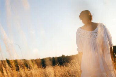 Vahşi tarladaki esmer genç kadın. Doğal güzellik ve romantizm kavramı. Gün batımı ışığı. Arkadan bak..