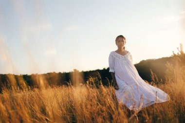 Vahşi tarladaki esmer genç kadın. Doğal güzellik ve romantizm kavramı. Gün batımı ışığı. Arkadan bak..
