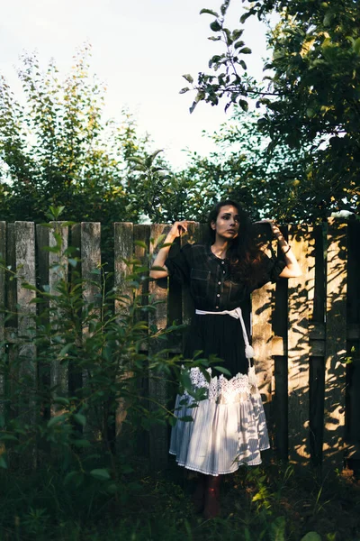 年轻时髦的女人站在花园或乡村房屋后院的篱笆边 例行公事 收获的概念 — 图库照片