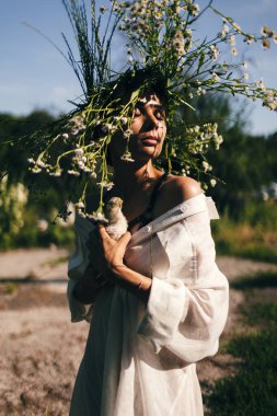 Güzel genç bir shuman kafasında papatya çelengiyle ve ellerinde civciv tutuyor..