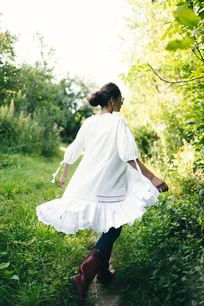 美丽的年轻印度女人 穿着白色的裙子 在公园里闻到花朵的芬芳 — 图库照片