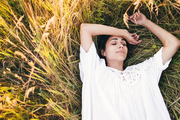漂亮的年轻女子躺在草地上 穿着一件白色的连衣裙 假期和人的概念 — 图库照片