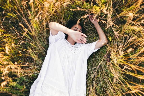 Beyaz Bir Elbise Giymiş Çimenlerin Üzerinde Yatan Hamile Bir Genç — Stok fotoğraf