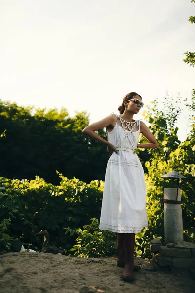 一个穿着白色衣服的漂亮女孩在花园里的画像 伯内特美丽的自然姑娘 穿着白色的衣服 在大自然中 在街上 在一棵树旁的花园里 化着妆 — 图库照片