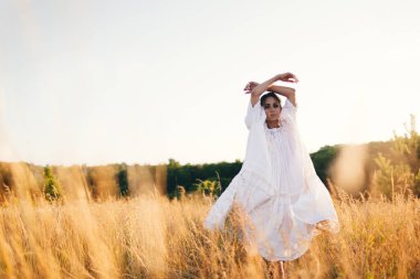 Vahşi tarladaki esmer genç kadın. Doğal güzellik ve romantizm kavramı. Gün batımı ışığı. Doğa, yaz tatili, tatil ve insanlar konsepti