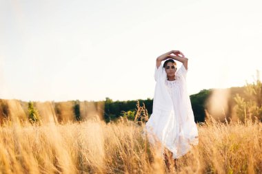 Vahşi tarladaki esmer genç kadın. Doğal güzellik ve romantizm kavramı. Gün batımı ışığı. Doğa, yaz tatili, tatil ve insanlar konsepti
