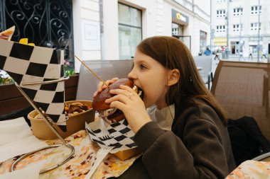 Şık hippi kız sulu burger yiyor. Caddedeki kafede nefis çizburger yiyen bir kız. Yaz zamanı. Yaz tatili pikniği. Metin için boşluk